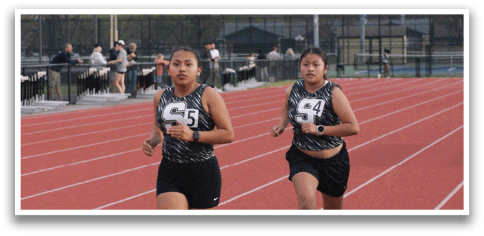 Two female runners are running on a track, with one of them wearing a black and white shirt. Contenido generado con IA