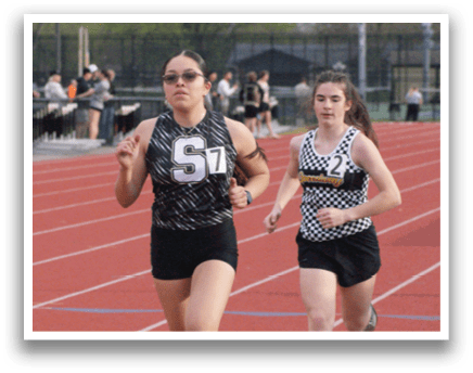 Two female runners are racing on a track, one wearing a black and white outfit and the other wearing a black and white and black outfit. Contenido generado con IA