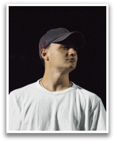 A man wearing a white shirt and a cap stands in a dark room. Contenido generado con IA