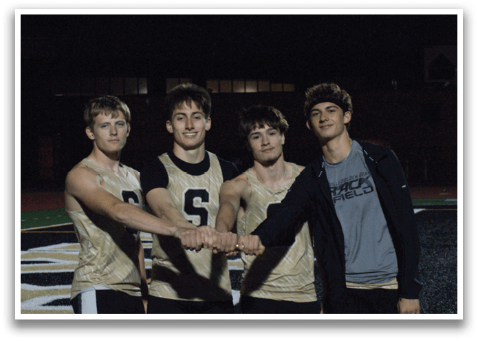 Four young men pose for a picture on a football field. Contenido generado con IA