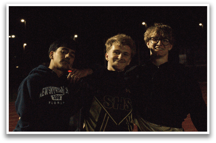 Three young men pose for a picture on a track. Contenido generado con IA