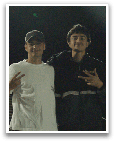 Two men pose for a picture at a stadium. Contenido generado con IA