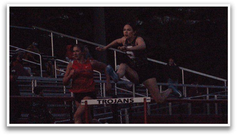 Two women are jumping over a barrier in a competition. Contenido generado con IA