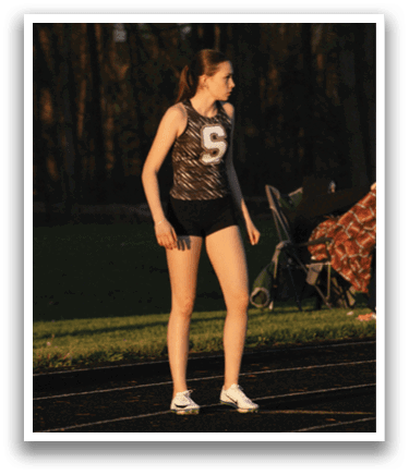 A female athlete is standing on a track, wearing a black and white uniform. She is the main focus of the image. Contenido generado con IA