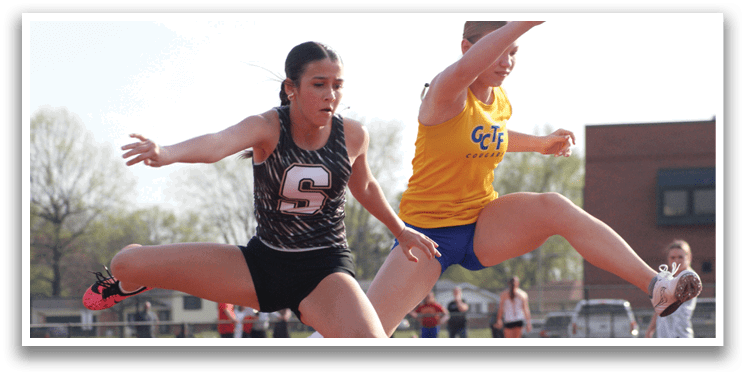 Two female athletes are jumping over a barrier during a competition. Contenido generado con IA