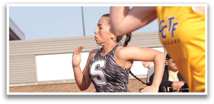 Two female runners are racing on a track, one wearing a black and white outfit and the other wearing a yellow shirt. Contenido generado con IA