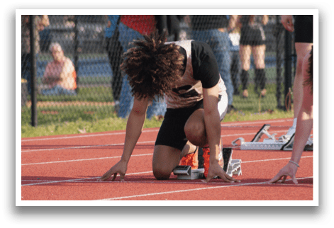 Two men are kneeling on a track, one with his head down and the other with his head up. They are both wearing black and white uniforms. Contenido generado con IA