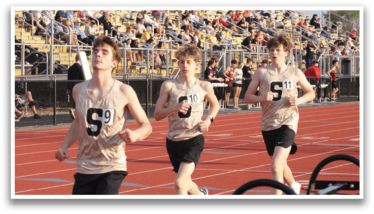 Three boys are running on a track in front of a crowd of people. Contenido generado con IA