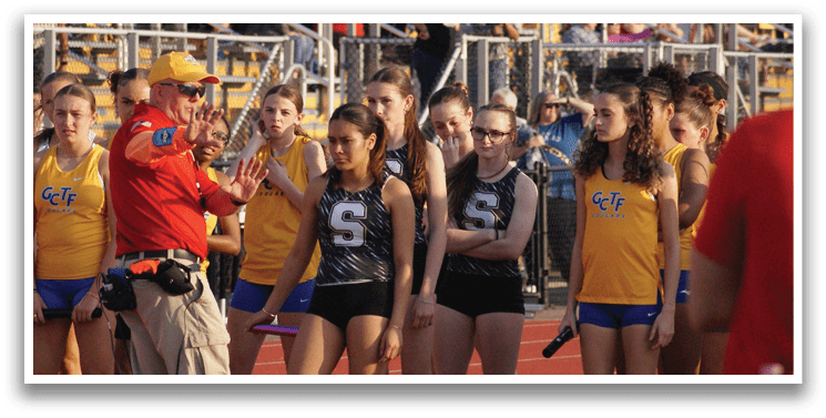A group of girls wearing yellow and blue uniforms stand on a track field. Contenido generado con IA