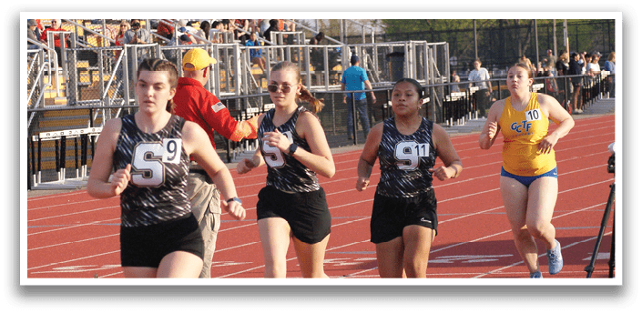 Four female runners are running on a track, with one of them wearing a number 6 shirt. They are running in front of a crowd of spectators. Contenido generado con IA
