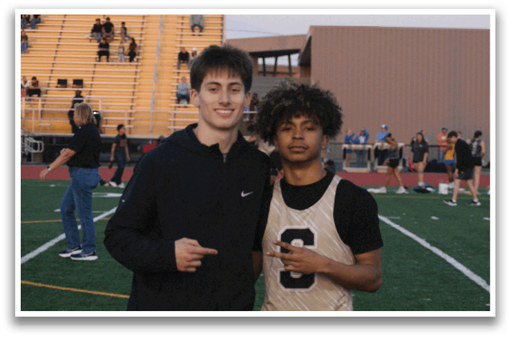 Two young men pose for a photo on a football field. Contenido generado con IA