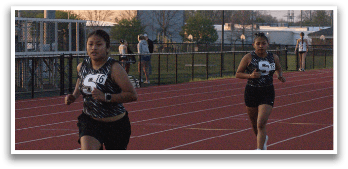 A group of people are running on a track, with one person wearing a yellow shirt. Contenido generado con IA