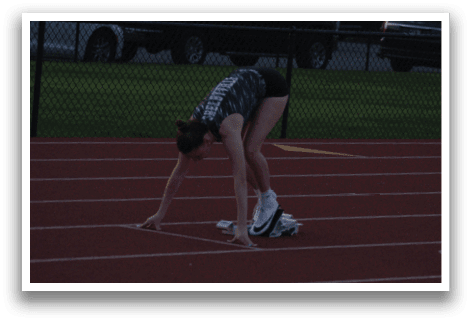 A woman is bending over on a track, possibly preparing to run. Contenido generado con IA
