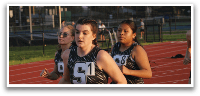 Three girls are running on a track, wearing sports uniforms. Contenido generado con IA