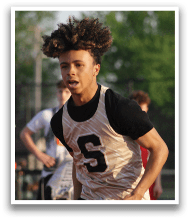 A young man wearing a jersey with the number 5 on it is standing on a field. Contenido generado con IA