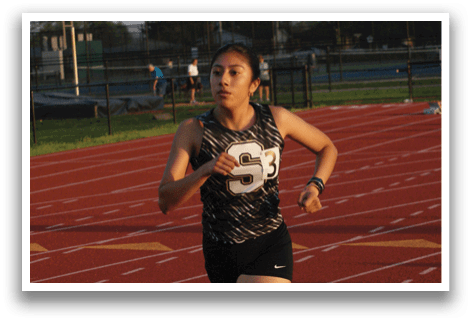 A woman is running on a track, wearing a black and white outfit. Contenido generado con IA