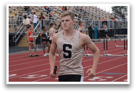 A runner wearing a gold shirt with the number 5 on it is running on a track. Contenido generado con IA
