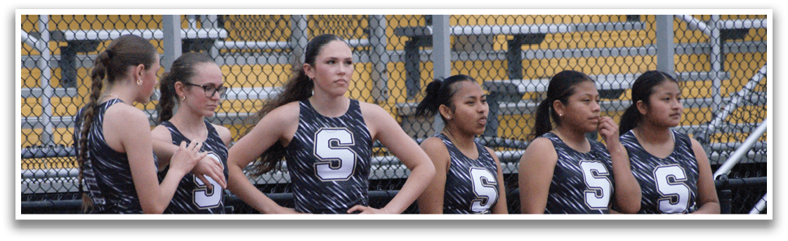A group of female athletes wearing uniforms and standing on a track. Contenido generado con IA