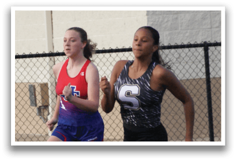 A group of girls are running on a track, with one girl leading the pack. Contenido generado con IA