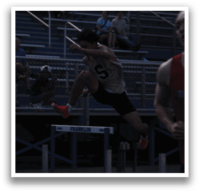 A man is jumping over a hurdle in a stadium, while a crowd watches. Contenido generado con IA