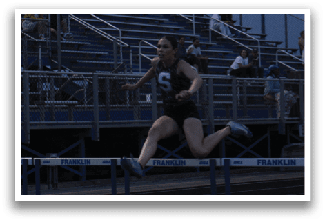 A female athlete is jumping over a barrier during a track and field event. Contenido generado con IA