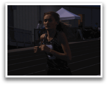 A woman is running on a track, wearing a black and white shirt. Contenido generado con IA