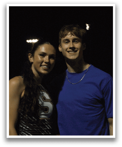 A man and woman are standing on a track, posing for a picture. The woman is wearing a black and white outfit. Contenido generado con IA