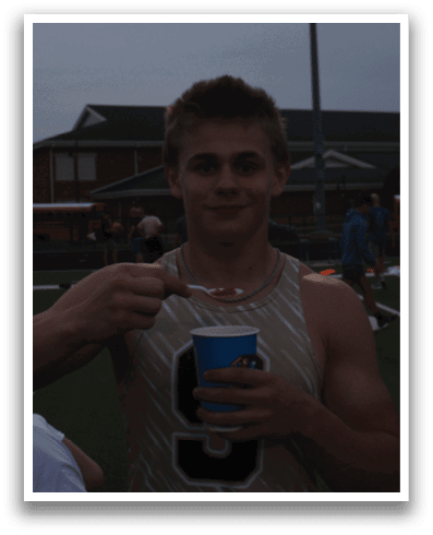 A man in a gold and black shirt is holding a blue cup with a red straw. Contenido generado con IA