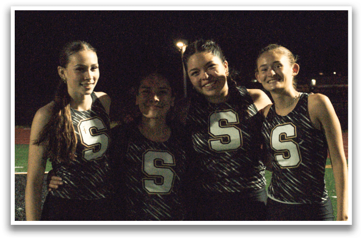 Four female athletes pose for a photo on a field. Contenido generado con IA