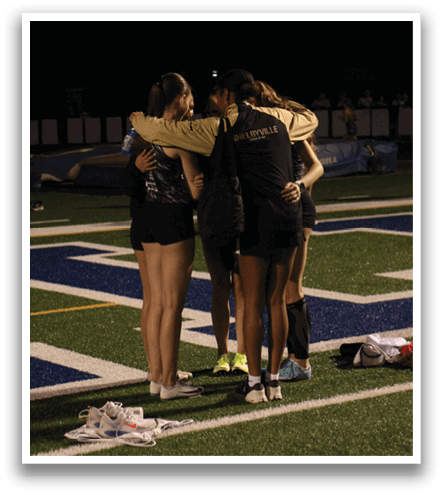Four women are hugging on a football field. Contenido generado con IA