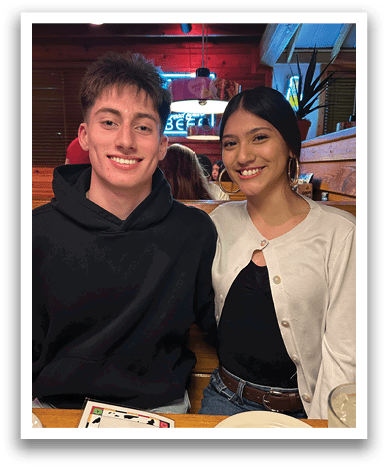 A man and woman are sitting at a table in a restaurant. They are smiling and posing for a picture. Contenido generado con IA