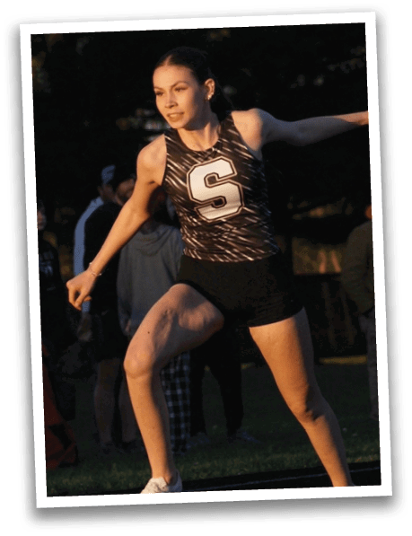 A woman wearing a black and white track suit is running on a track. Contenido generado con IA