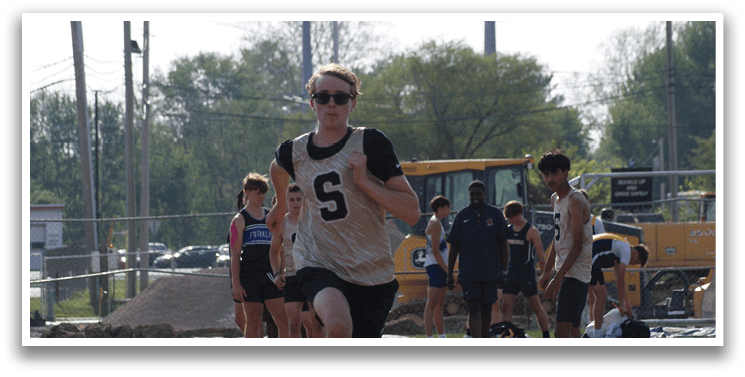 A group of people are running on a track, with one man wearing a number 5 shirt. Contenido generado con IA