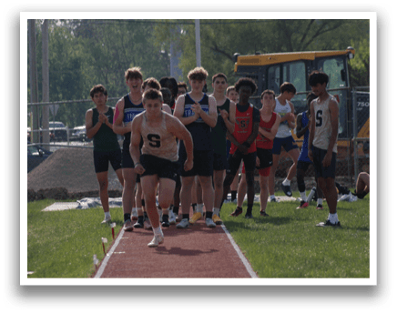 A group of people are standing on a track, with some of them holding their hands up. A man is running on a track, and there are several other people watching him. Contenido generado con IA
