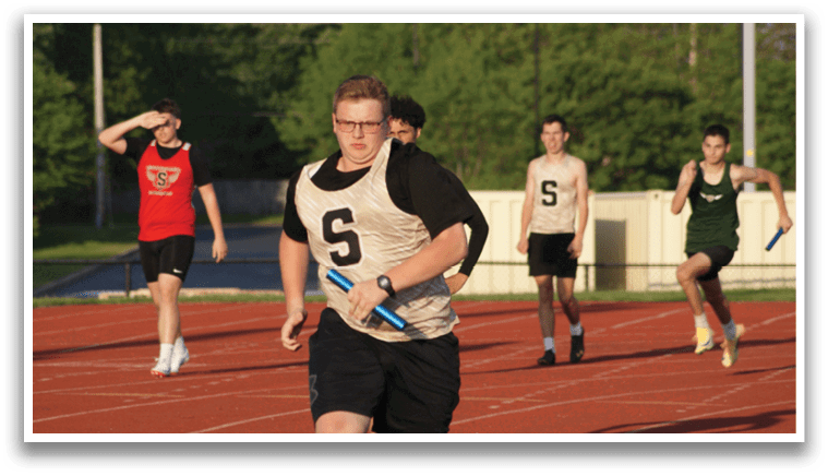 A group of people are running on a track, with one man wearing a white shirt and black shorts. Contenido generado con IA