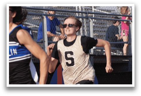 Two people are running on a track, one wearing a black and blue uniform and the other wearing a gold and black uniform. Contenido generado con IA