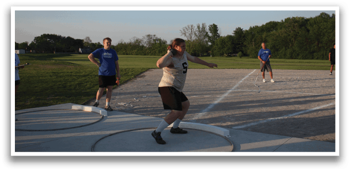 A group of people are standing on a track, with one person throwing a frisbee. Contenido generado con IA