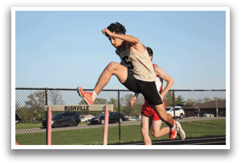A man is running on a track, jumping in the air. Another man is running behind him. Contenido generado con IA