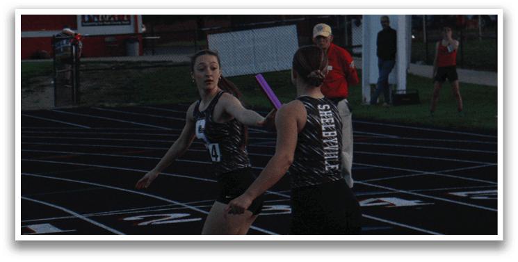 A group of girls are running on a track, with one girl holding a pink bat. Contenido generado con IA