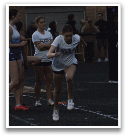 A group of people are standing on a track, with one person throwing a frisbee. Contenido generado con IA