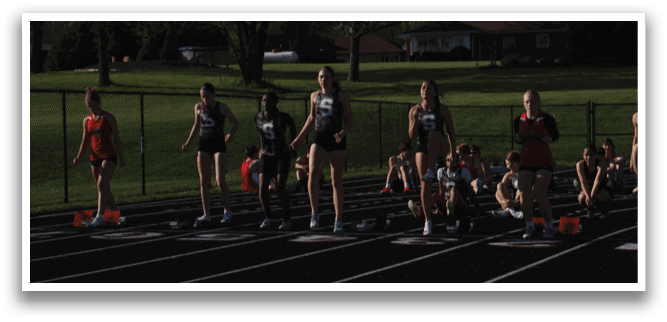 A group of girls are lined up on a track, getting ready to run. Contenido generado con IA