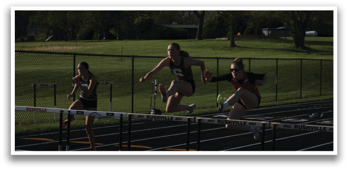 Three girls are jumping over a barrier on a track. Contenido generado con IA