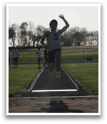 A man is jumping in the air on a track, possibly in a competition. Contenido generado con IA