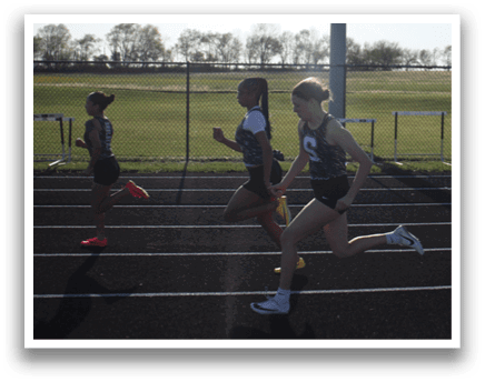 Two girls are running on a track, one in the lead. Contenido generado con IA