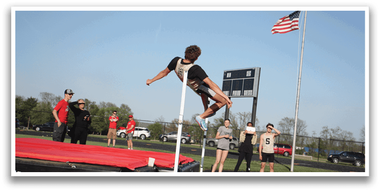A man is jumping over a pole on a track, with several people watching. Contenido generado con IA
