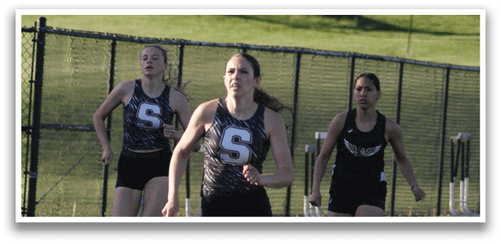 Three female runners are running on a track, with one of them wearing a number 5 shirt. Contenido generado con IA