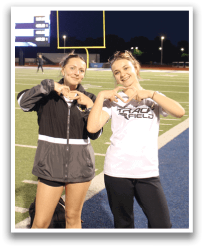 Two women pose for a picture on a football field. Contenido generado con IA