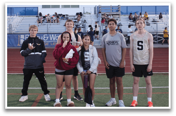 A group of young people pose for a photo on a field in front of a stadium. Contenido generado con IA