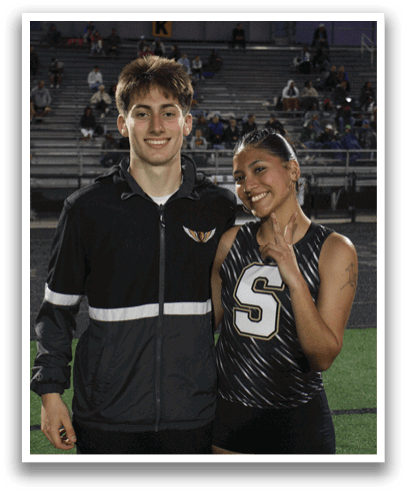 A man and a woman are standing on a field, both wearing sports uniforms. The woman is holding up her number, which is 5. Contenido generado con IA