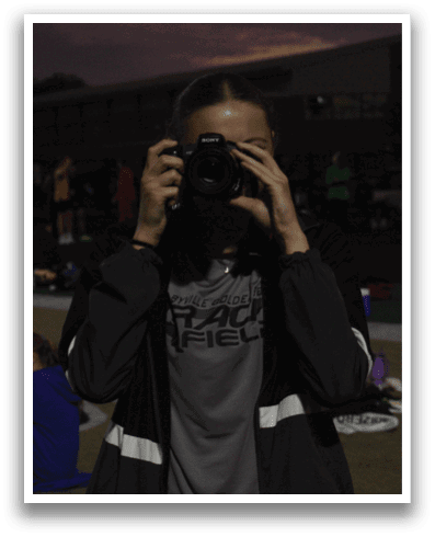 A person is taking a picture of a group of people sitting on the ground. Contenido generado con IA